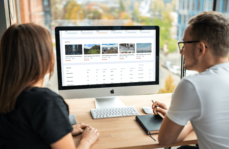 A man and woman at a desk looking at the StoryScale interactive demo platform