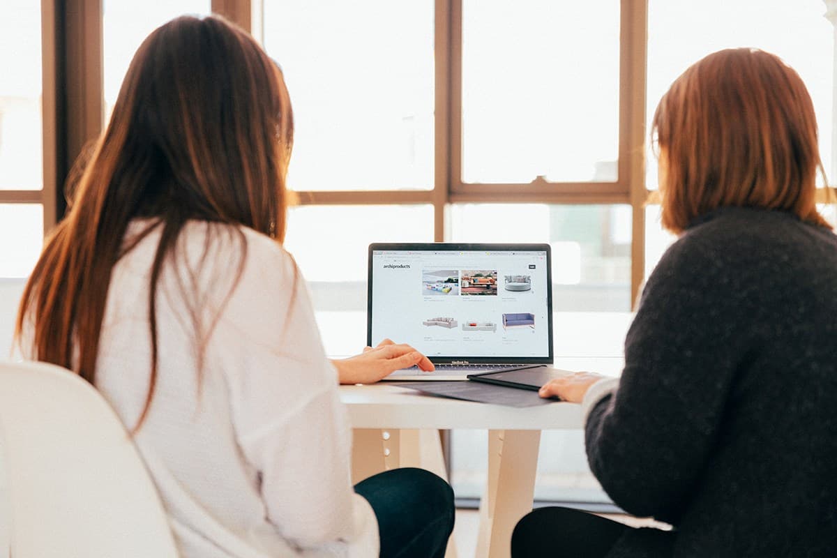 Trainer walking a new hire through a product tutorial on a laptop